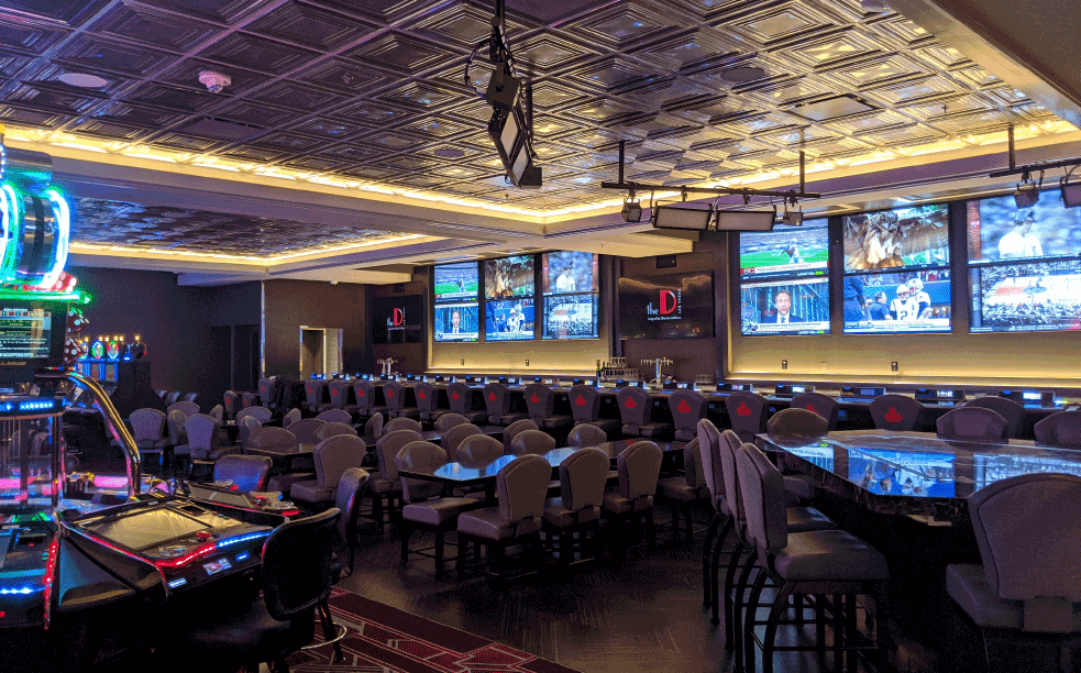 The D casino sportsbook lounge with video screens and bar seating